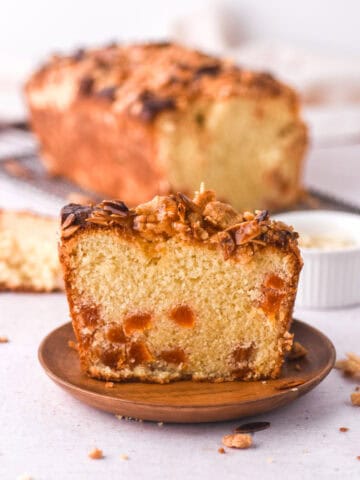 A slice of the loaf cake in shown in front of the whole loaf. You can see the crunchy topping.