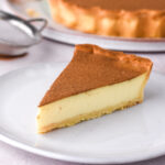 A perfect slice of traditional milktart on a plate. You can see the layer of pastry, custard, and cinnamon topping.