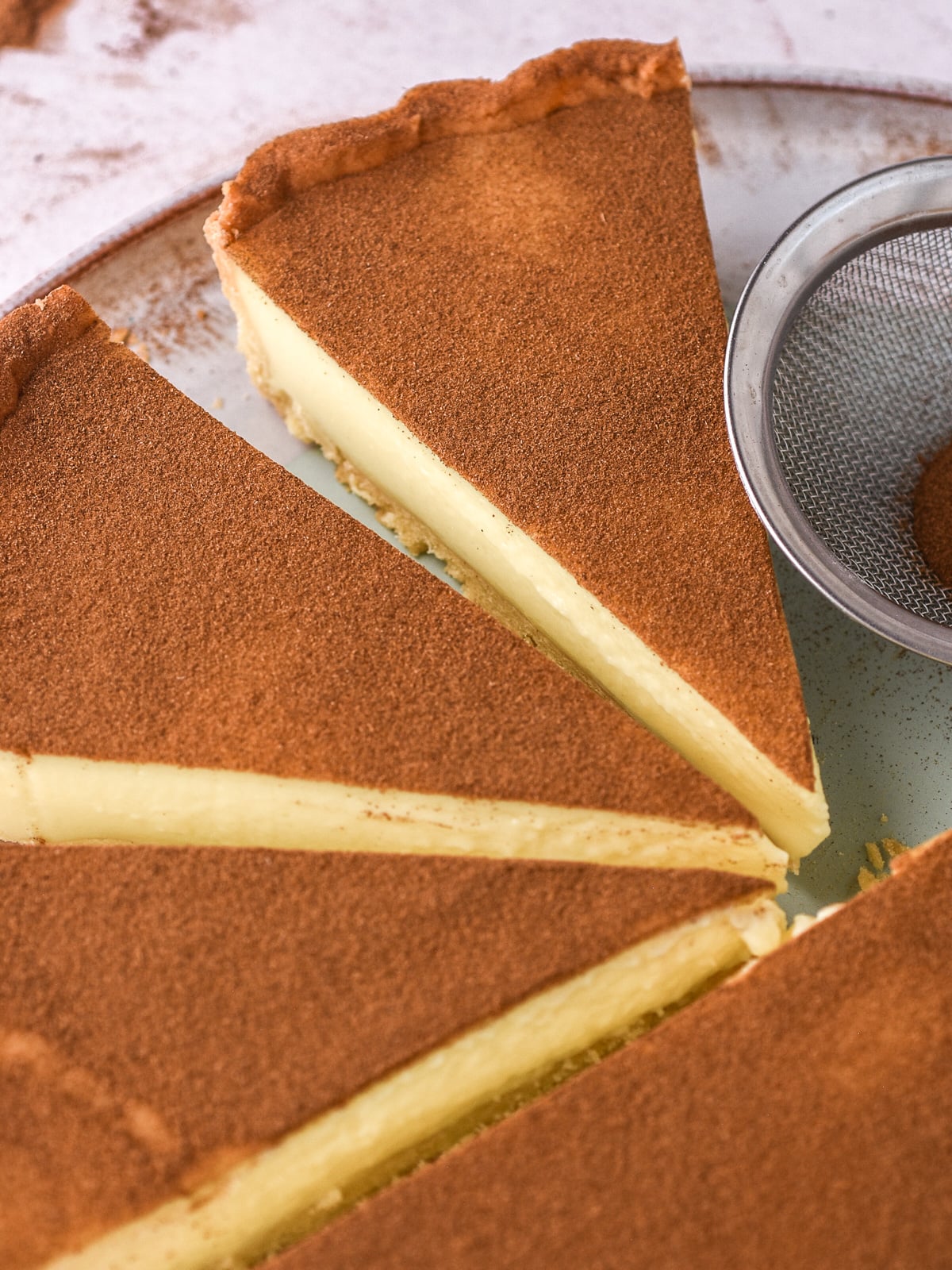 Image shows the whole milktart cut into slices on a large serving plate.