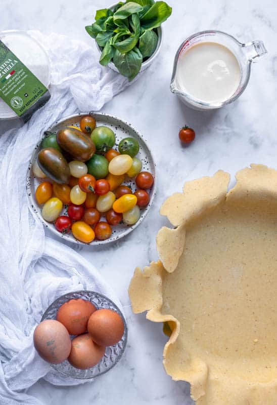 Burrata Cheese and Tomato Quiche being made, all the ingredients on the counter top 