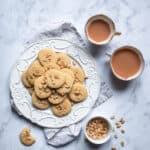 Salty Sweet Peanut Butter Shortbread Cookies on a cake plate next to two cups of tea