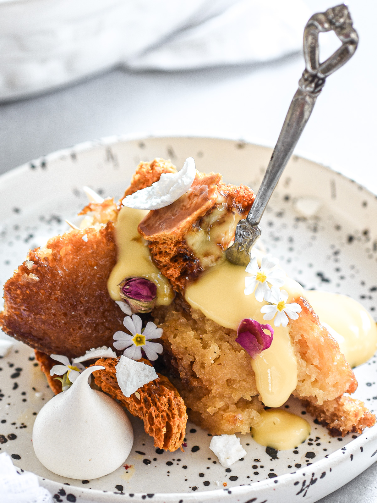 Image shows a serving of malva pudding on a plate drenched in custard.