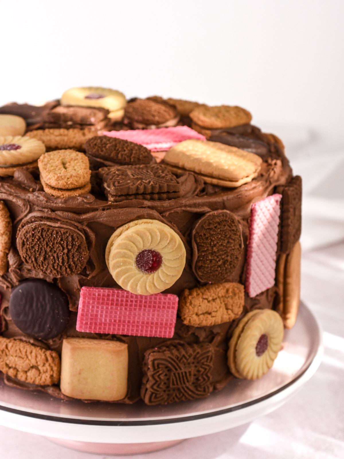 Image shows a large chocolate cake covered in an assortment of different shaped biscuits.