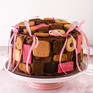 Image shows full on a pink cake stand. It's decorated with ink ribbons and an assortment of biscuits.