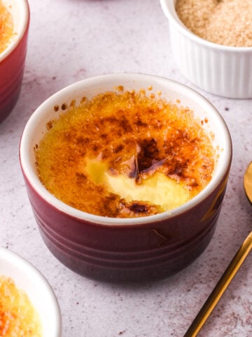 Image shows the crème brûlée with the sugar crust that has been cracked next to a spoon.