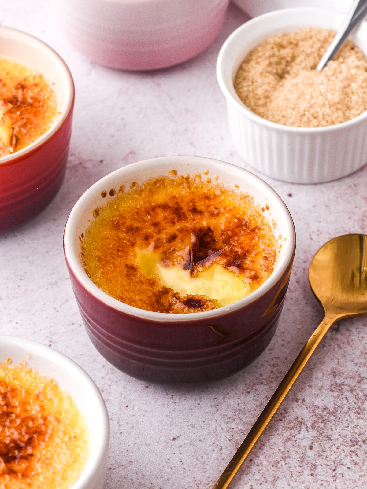 Image showing a white chocolate creme brulee next to a small ramekin filled with brown sugar.