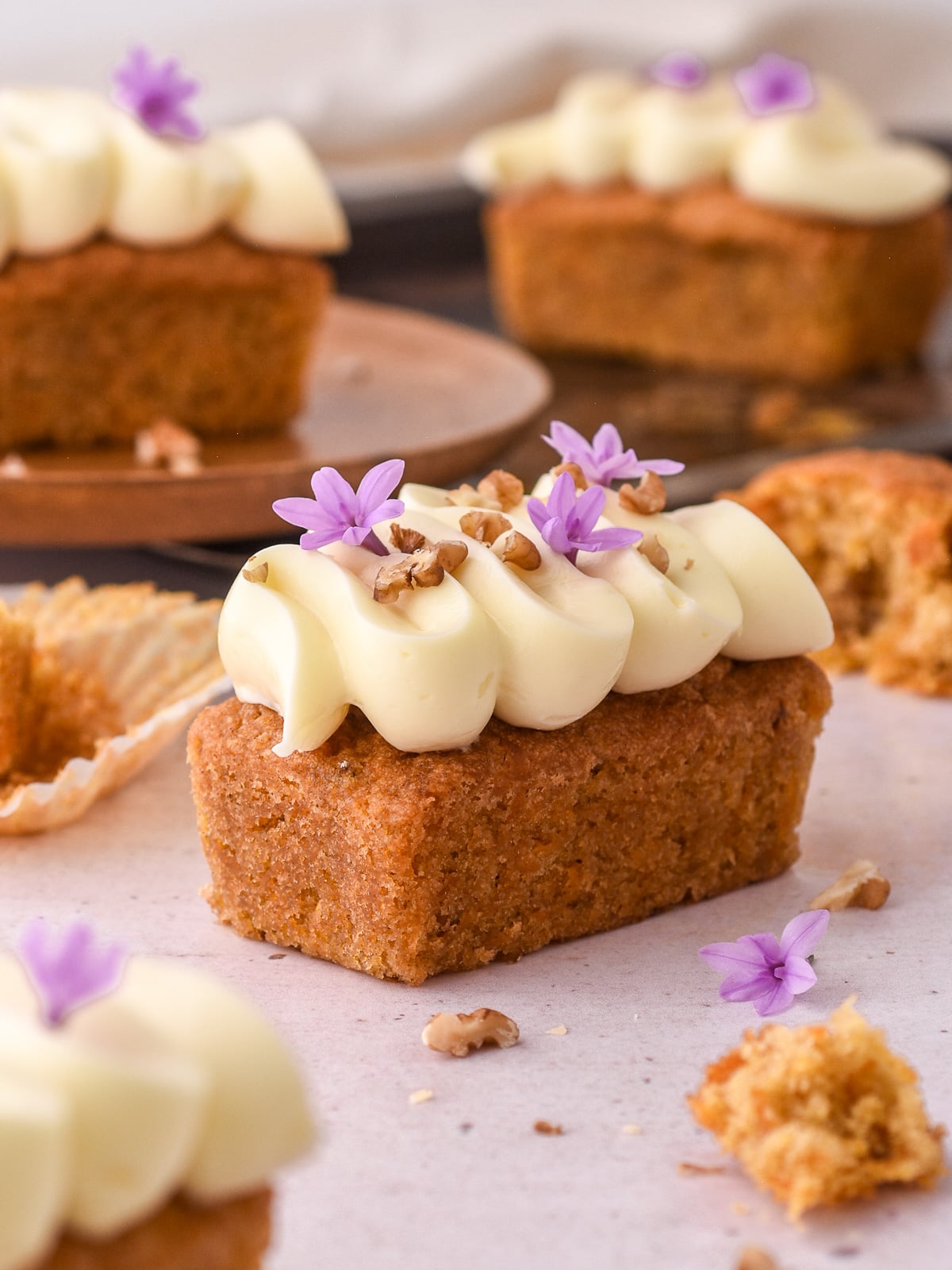 Mini carrot loaf cake shown from the side,, you can see the generous piping of frosting on top of the cake.
