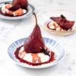 Red wine poached pears shown on a plate with honey flavoured yogurt