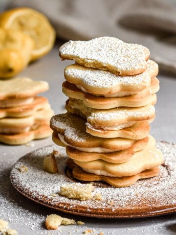 Lemon Sandwich Cookies filled with lemon buttercream shown stacked on top of one another.