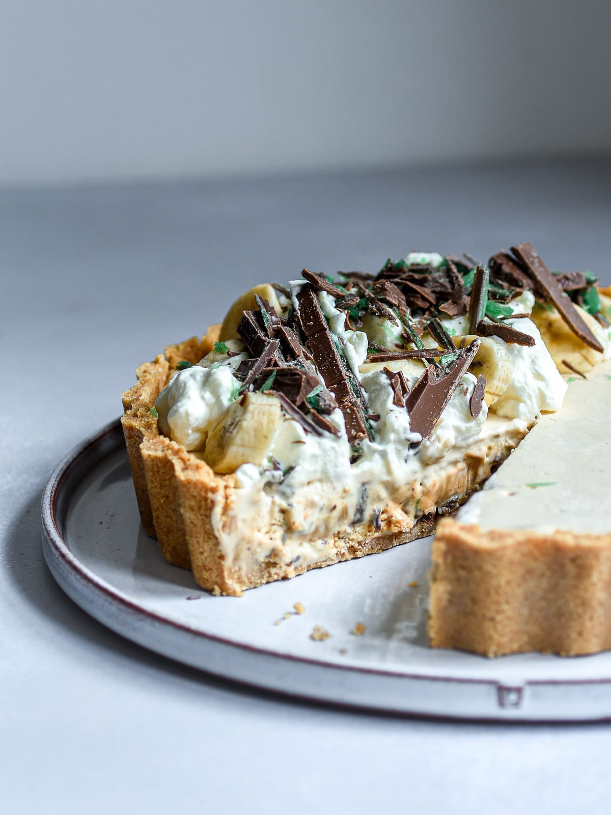 Peppermint crisp tart with caramel and Tennis biscuits shown on a cake plate with a slice missing.