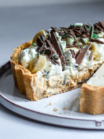 Peppermint crisp tart on a cake plate with a slice missing.