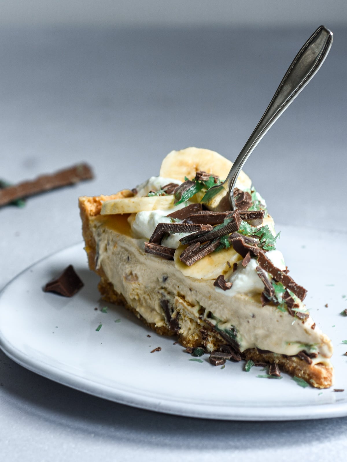 A slice of peppermint crisp tart shown on a plate with a form sticking through the top of the tart.