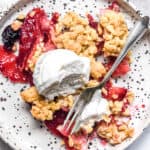 Apple and Blackberry Crumble shown from above on a plate with ice cream.