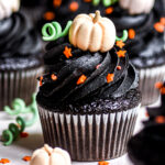 Black Velvet Halloween Cupcakes shown decorated with black buttercream frosting and edible mini pumpkins and orange stars.