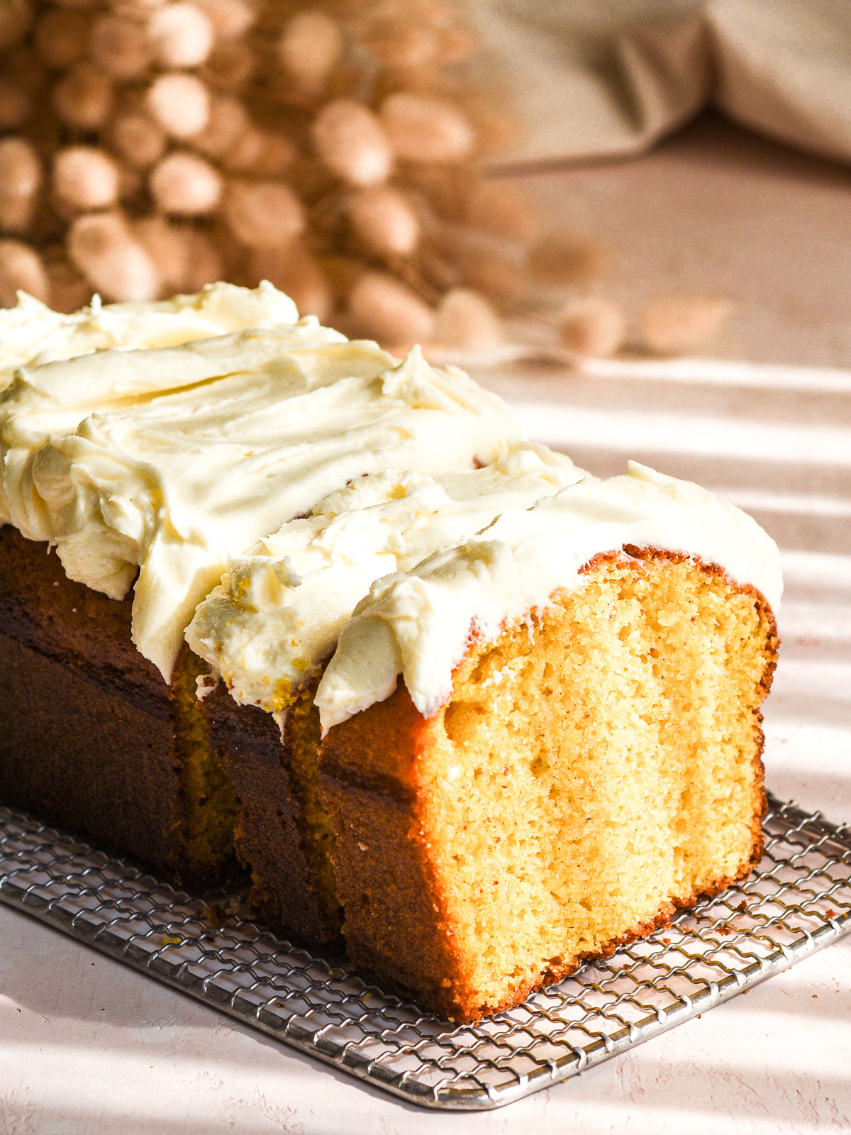Pumpkin Bread with Cream Cheese Frosting shown sliced on a wire rack.