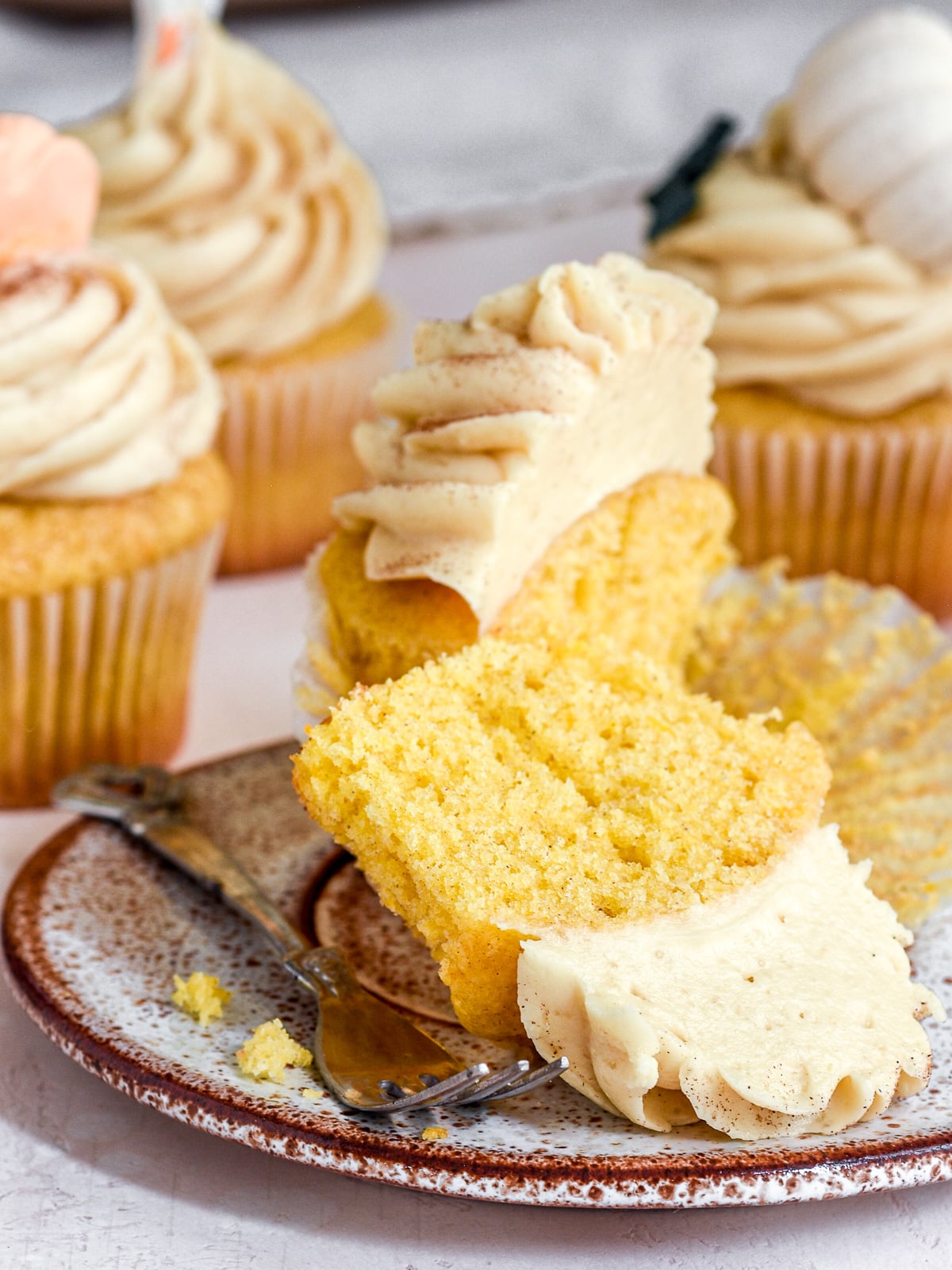Image shows a pumpkin Halloween cupcake sliced in half so that you can see the fluffy texture of the cupcake.