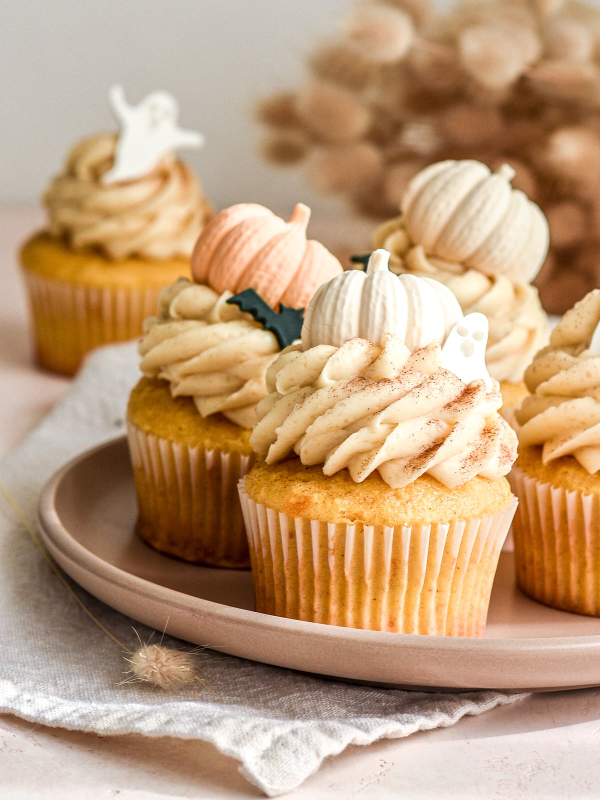 Pumpkin Halloween Cupcakes swirled with brown sugar cream cheese frosting on a side plate on a kitchen counter.