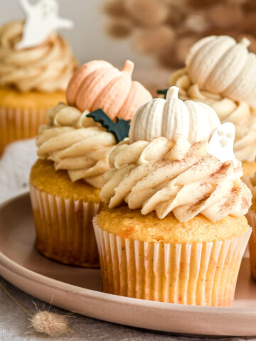 Pumpkin Halloween Cupcakes with Brown Sugar Cream Cheese Frosting shown on a small plate on a kitchen counter.