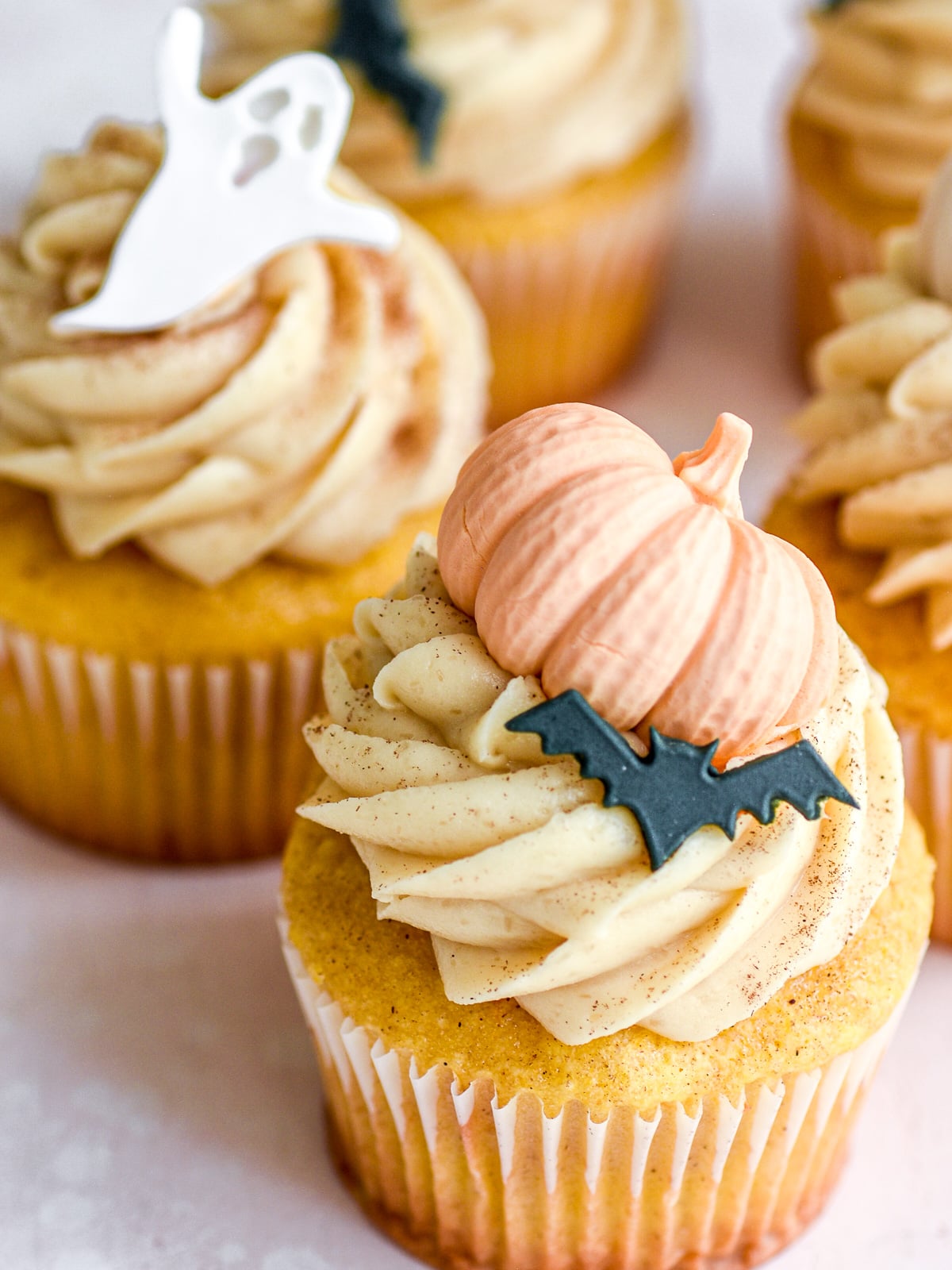 Image shows Pumpkin Halloween Cupcakes with Brown Sugar Cream Cheese Frosting decorated with edible pumpkins, bats, and ghosts.