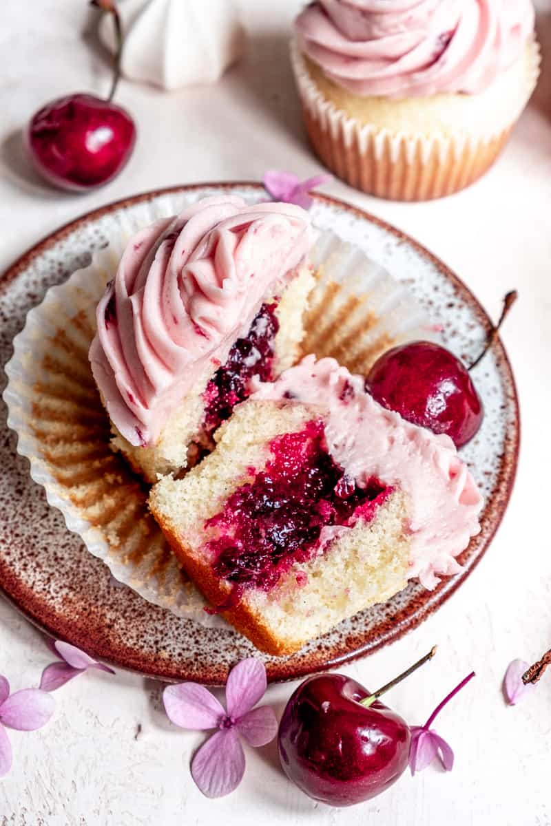 Cherry Cupcake on a plate, sliced in half showing the cherry filling center. 