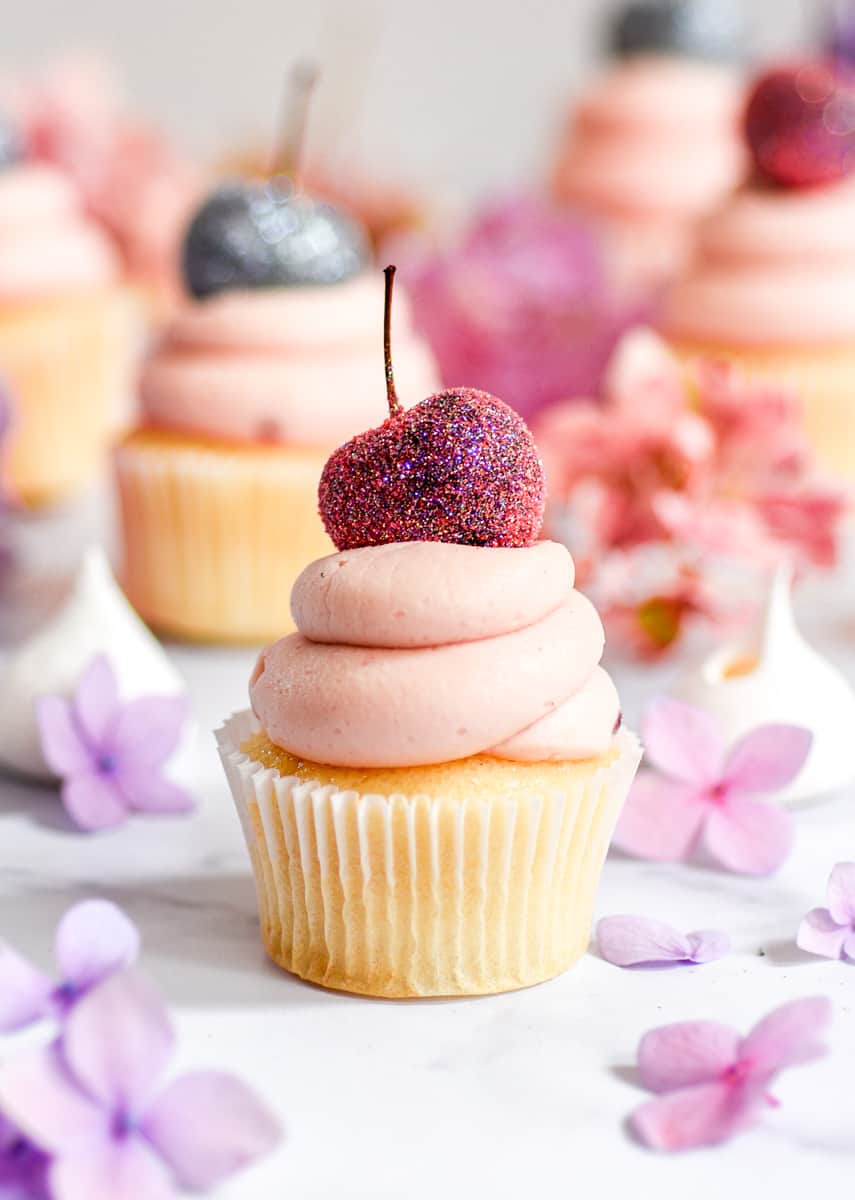 Cherry Frosting shown on a mini cupcake with a glitter dusted cherry on top.