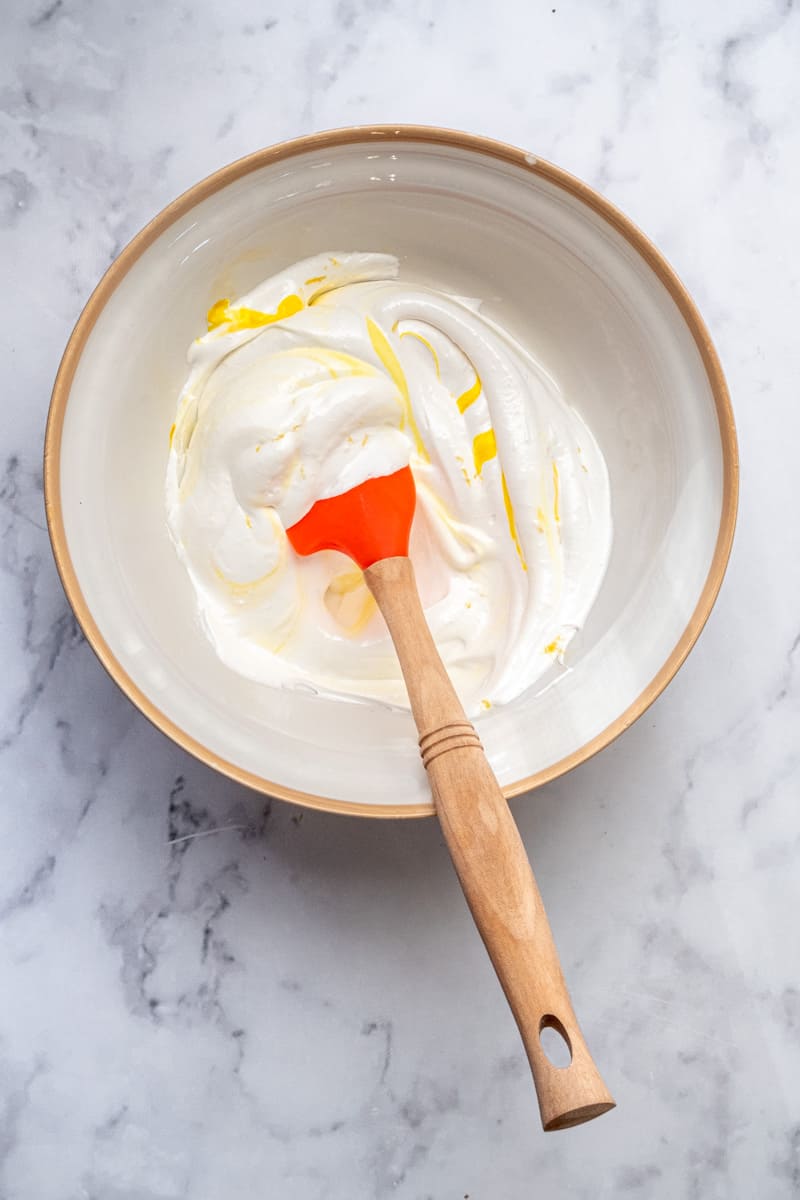 Image showing step 7, the yellow food colouring being swirled through the meringue mixture. 