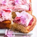 Summer Raspberry Cake shown on a cake plate with. slice cut out.