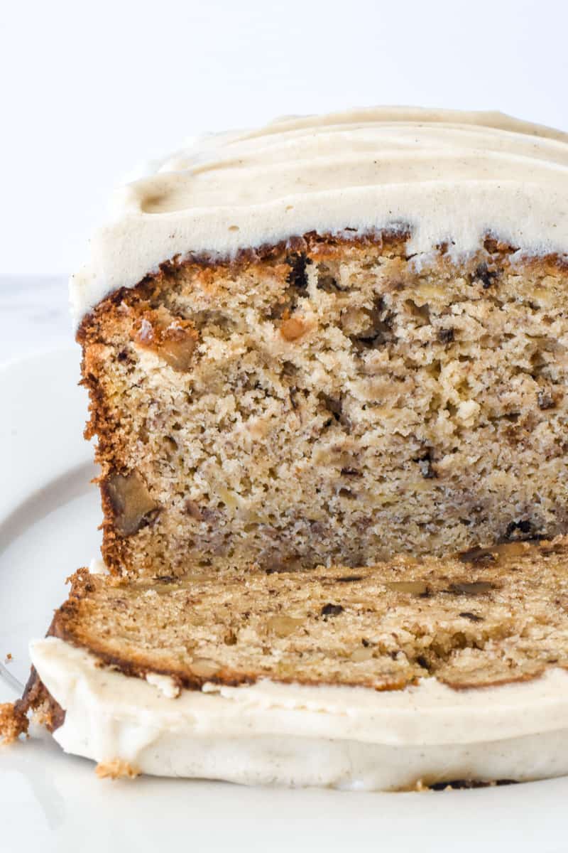 Banana Bread with Cream Cheese Frosting shown up close with a slice missing to show the texture of the loaf.