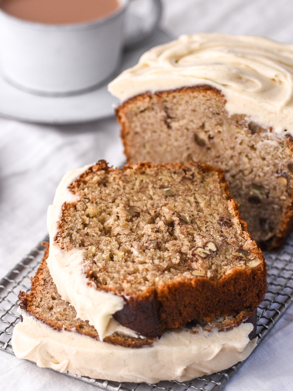 Wire rack shown packed with slices of banana bread with cream cheese frosting.