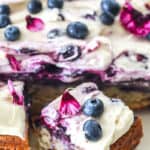 Blueberry Banana Cake shown on a cake plate with square slices cut.