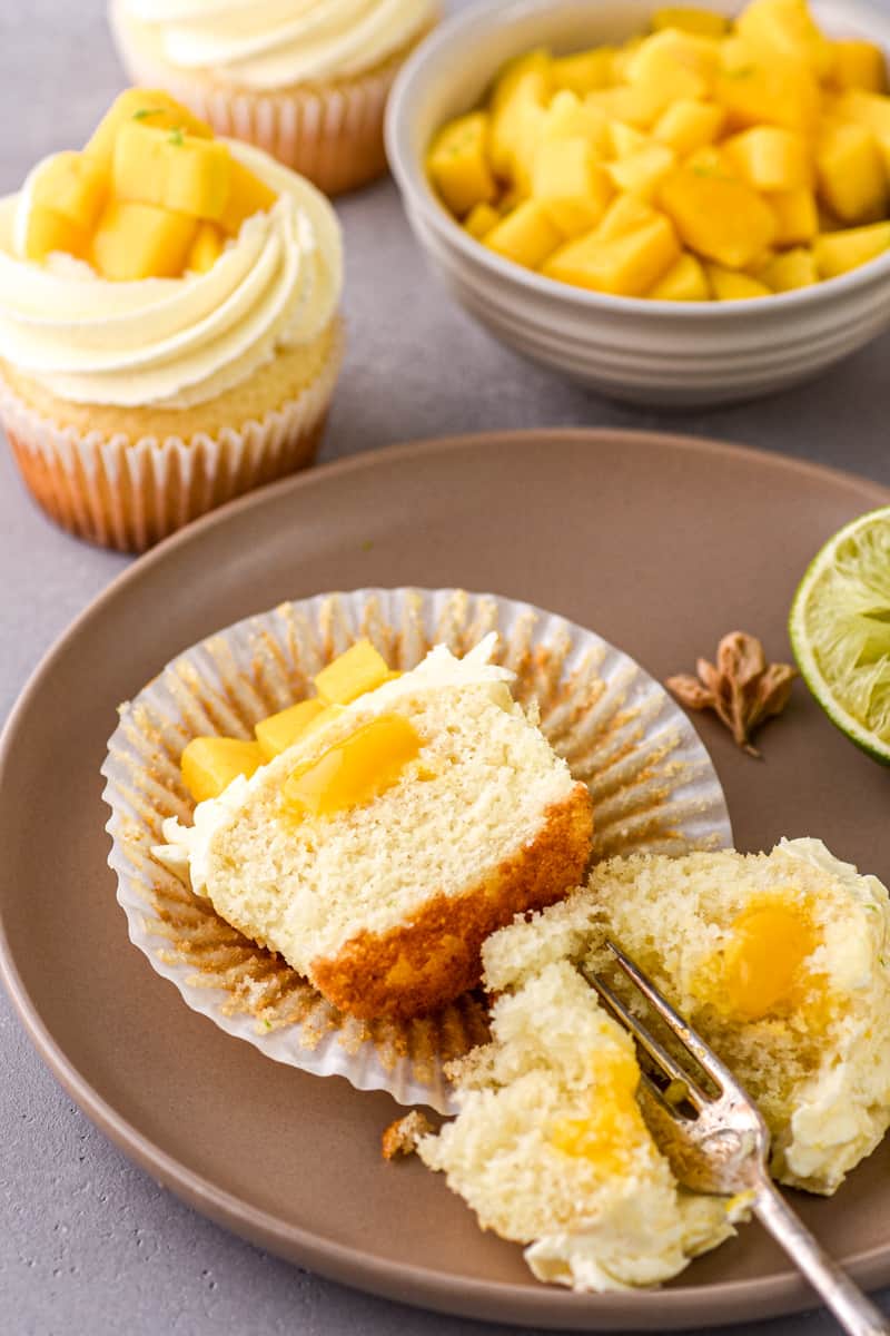 Mango Cupcake shown on a plate cut in half t show the mango purée center. 