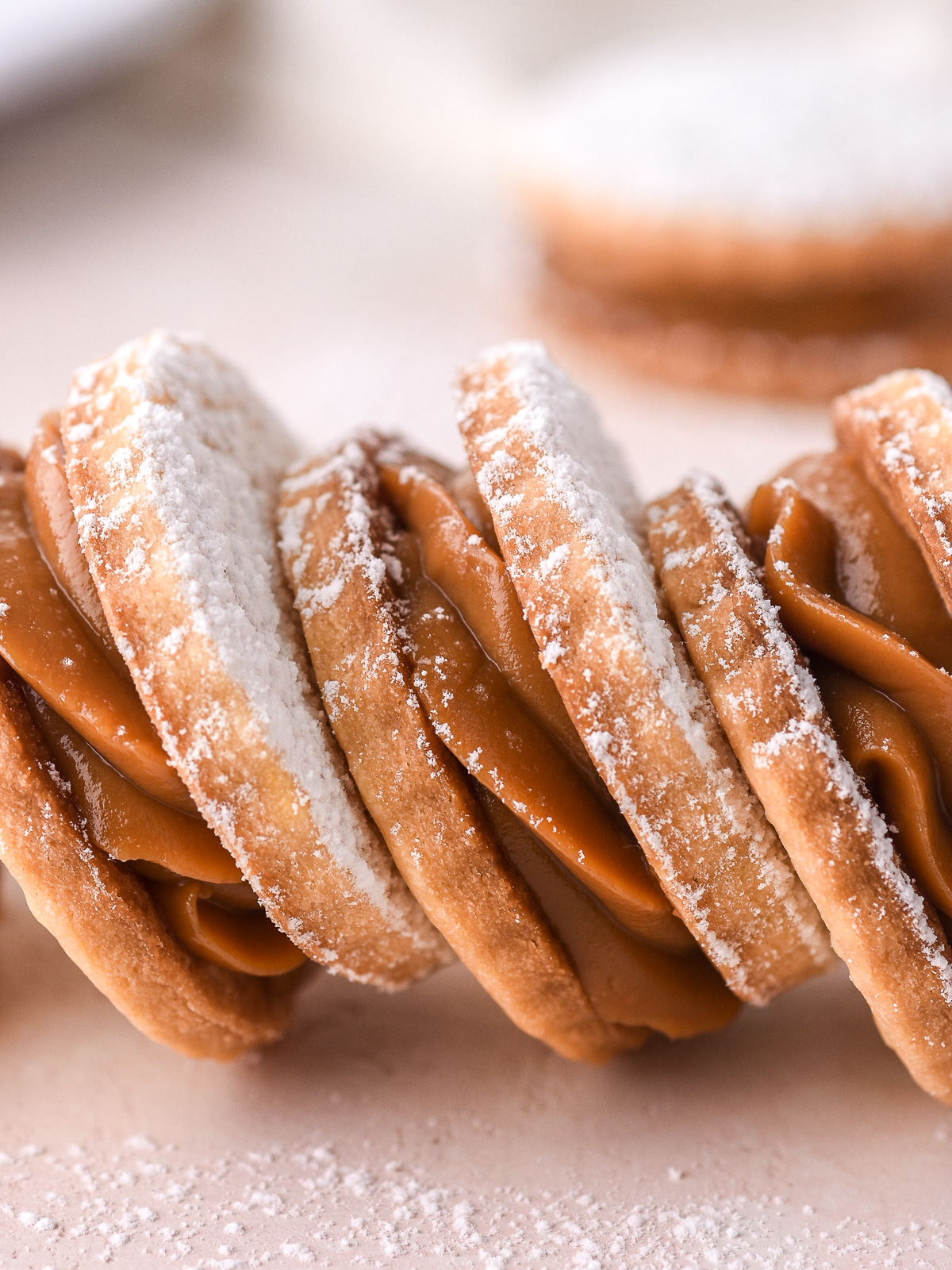 Dulce de Leche Cookies shown in a row on a light pink counter.