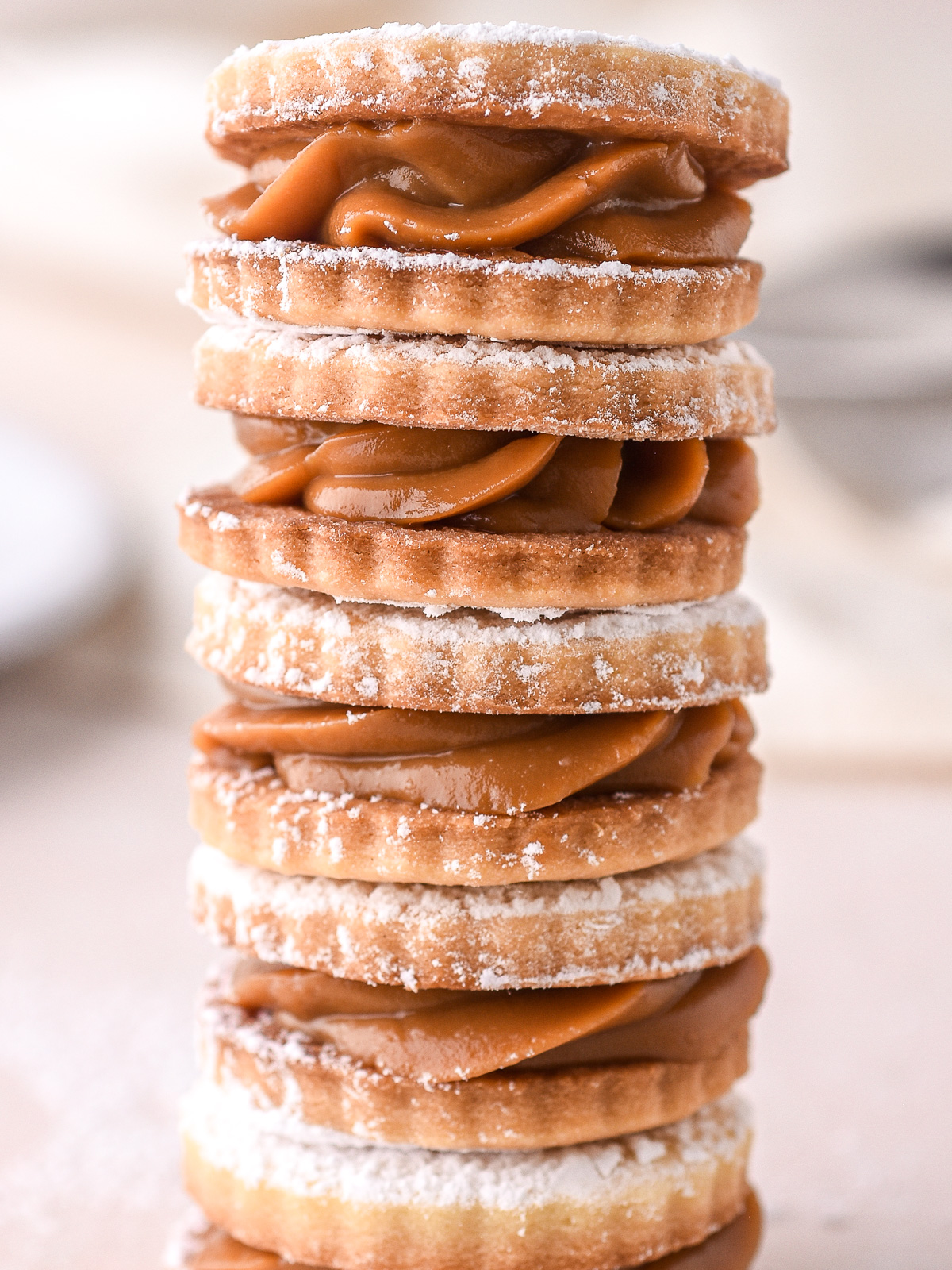 Caramel filled cookies shown in a long stack on a kitchen counter.