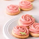 Buttercream cookies shown on a white cake plate on a kitchen counter