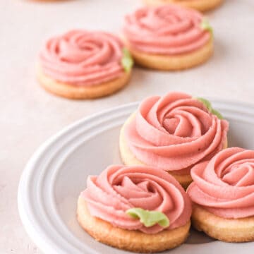 Buttercream cookies shown on a white cake plate on a kitchen counter
