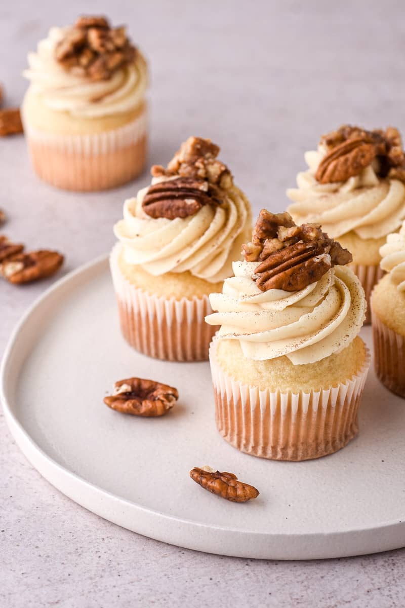 Pecan Pie Cupcakes shown on a white round plate on a nutral coloured  kitchen counter.