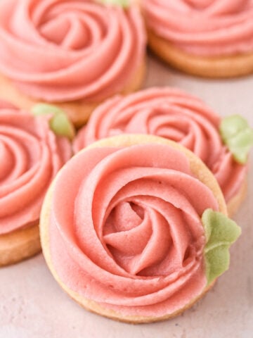 Rose buttercream cookies shown decorated on a counter top/