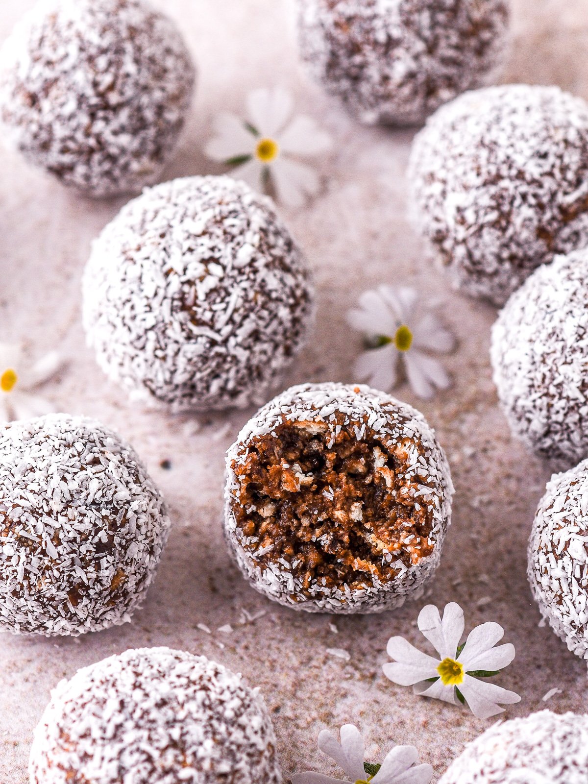 Condensed milk truffles shown on a counter top, one has been bitten into and you can see the chocolatey inside of the truffle.