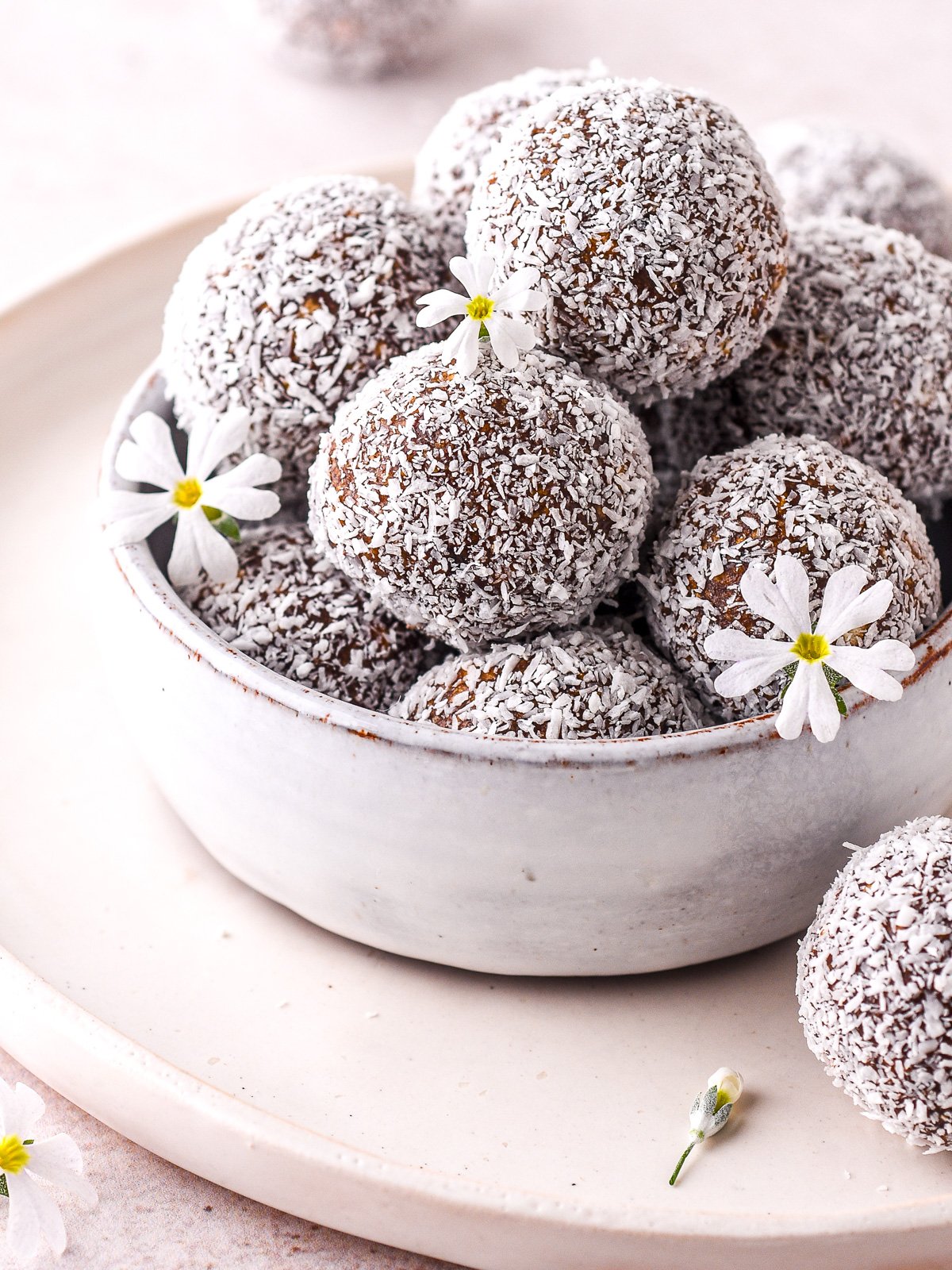 A pile of coconut covered condensed milk chocolate truffles in a small bowl.