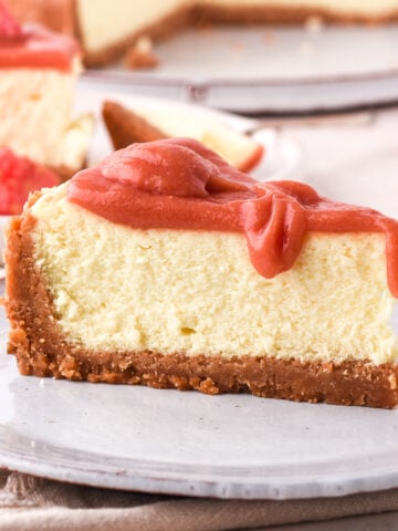 Slice of guava cheesecake shown up close, there is guava compote dripping off the top of the slice.