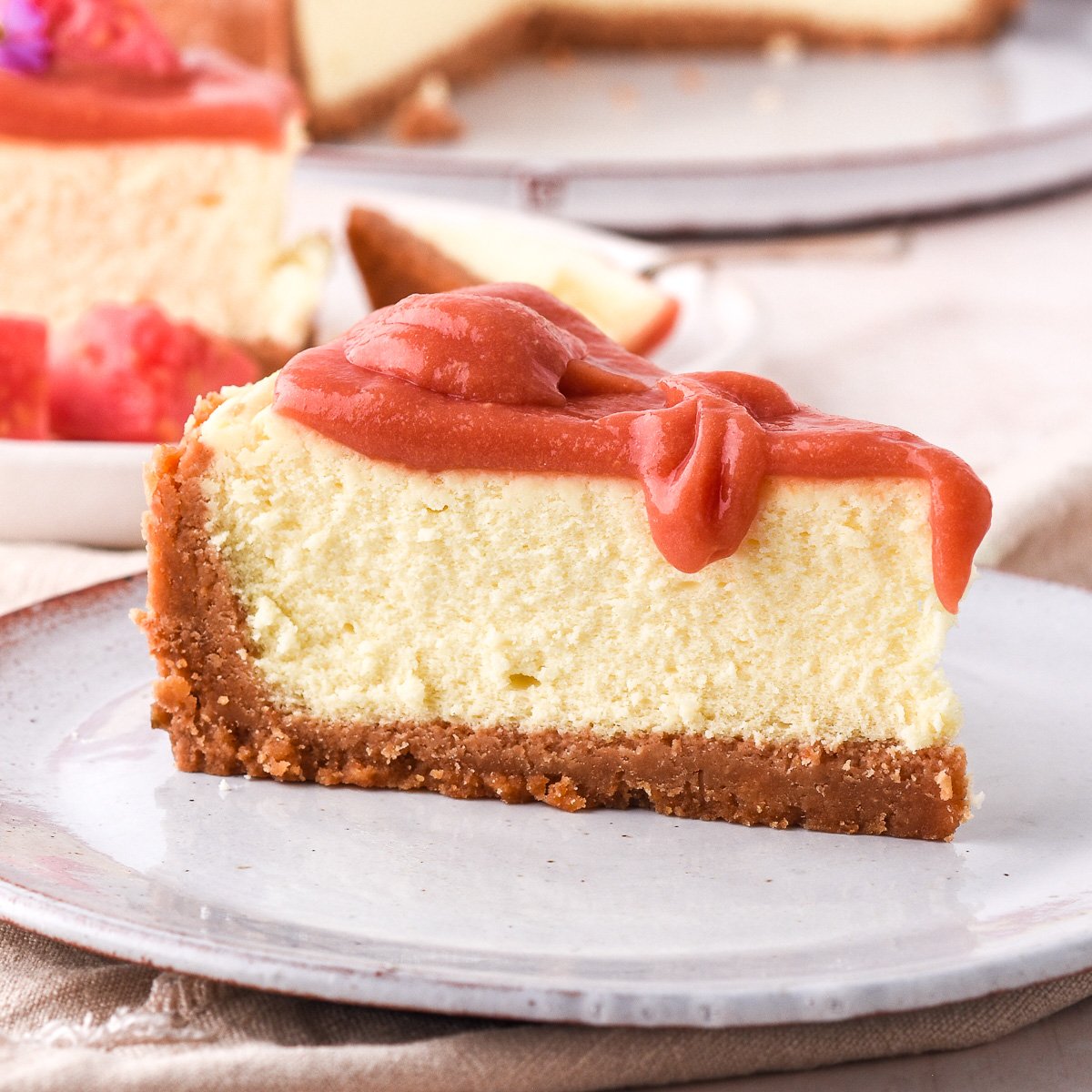 Slice of guava cheesecake shown up close, there is guava compote dripping off the top of the slice.