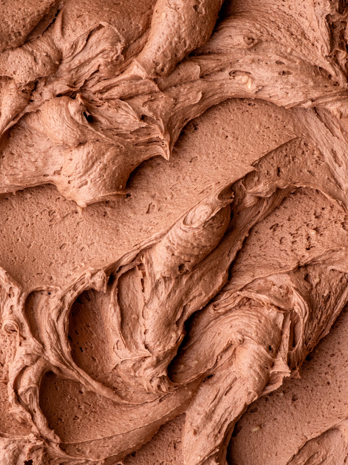 Fluffy Nutella buttercream frosting shown swirled on a flat surface so that you can see the texture.