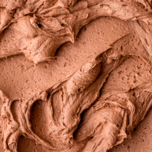 Fluffy Nutella buttercream frosting shown swirled on a flat surface so that you can see the texture.