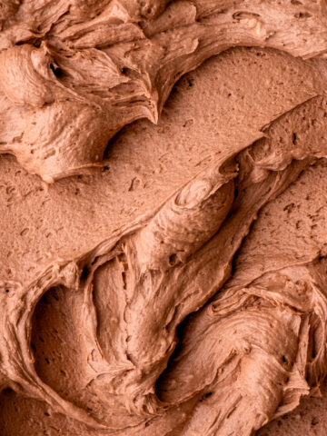 Fluffy Nutella buttercream frosting shown swirled on a flat surface so that you can see the texture.
