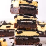Cheesecake Oreo Brownies shown in a stack so that you can see the layers of brownie, oreos, and cheesecake