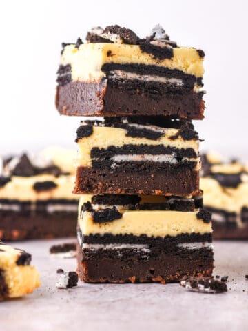 Cheesecake Oreo Brownies shown in a stack so that you can see the layers of brownie, oreos, and cheesecake