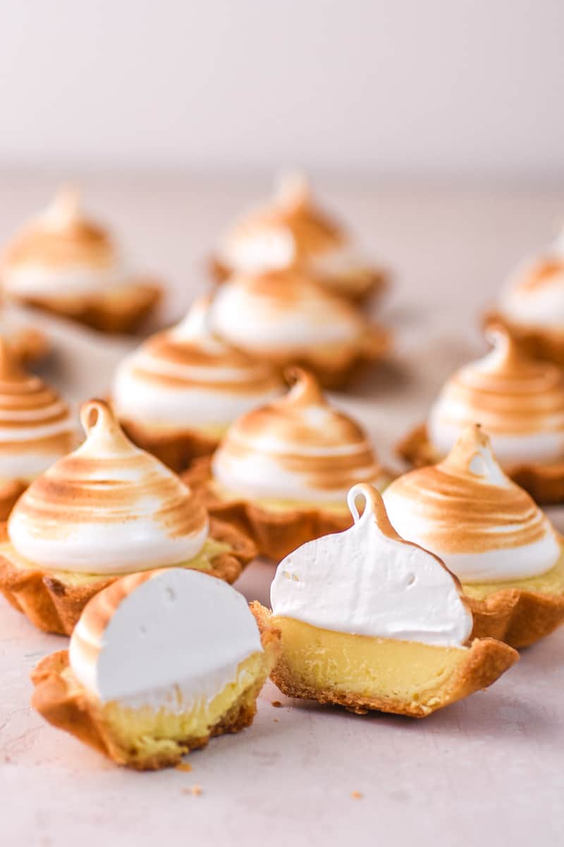 Mini Lemon Meringue Tart shown on a kitchen counter, the one in front is cut in half