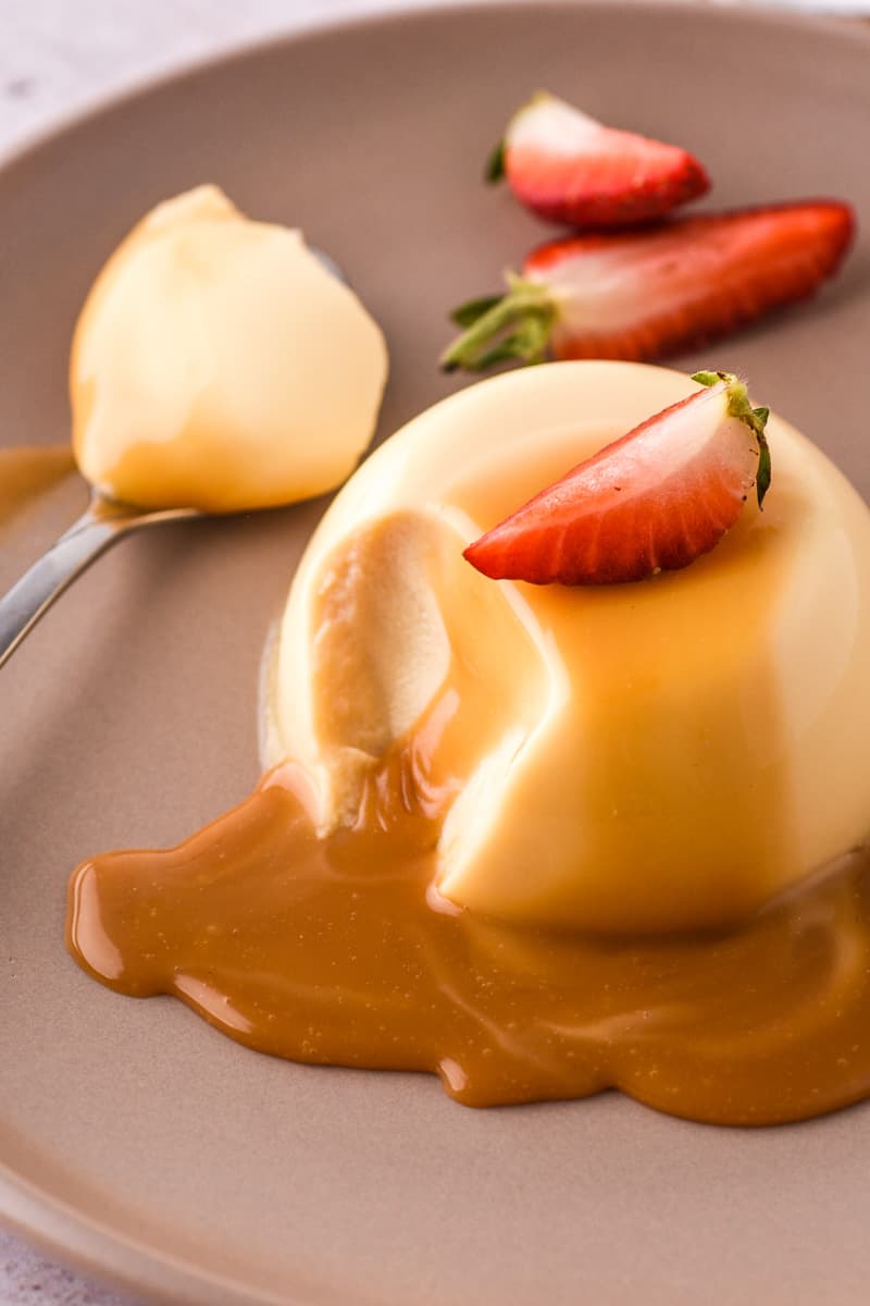 Baileys Panna Cotta shown on a plate with chocolate sauce and fresh strawberries.