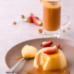 Baileys panna cotta shown on a plate with strawberries and caramel chocolate sauce