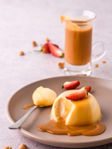 Baileys panna cotta shown on a plate with strawberries and caramel chocolate sauce